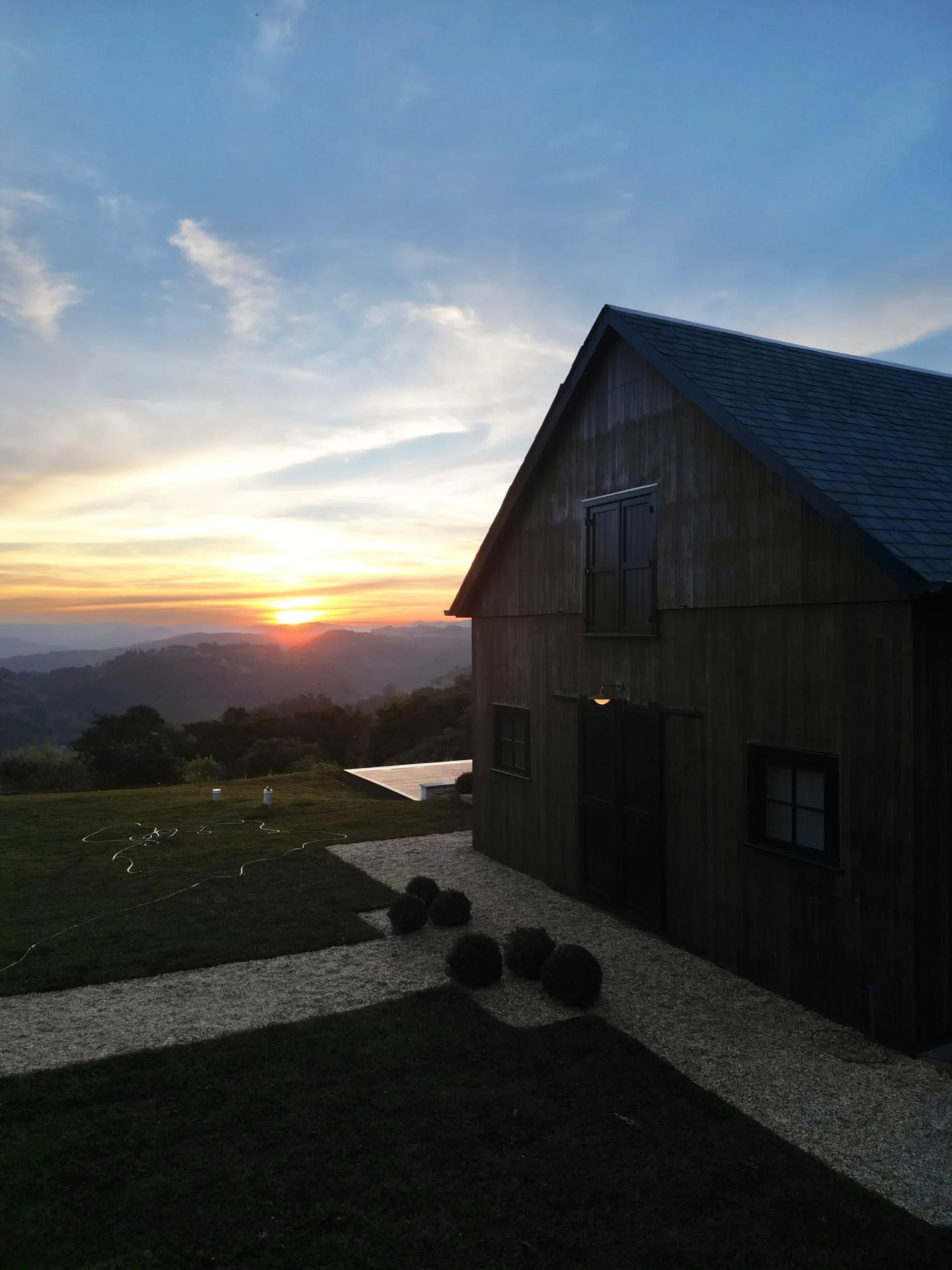 O celeiro da Felix Hills Barn em silhueta, com o sol se pondo atrás dos morros